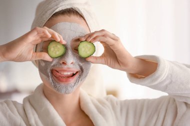 Evde kilden maskeli ve salatalık dilimli genç bir kadın var.