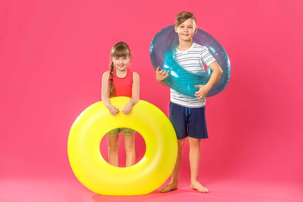 Carino bambini piccoli con anelli gonfiabili su sfondo di colore — Foto Stock