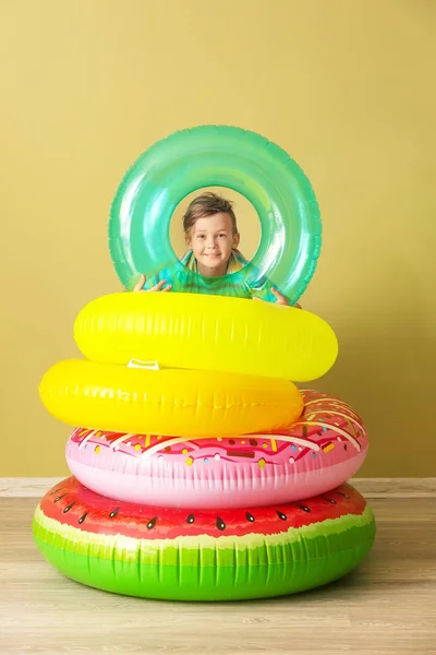 Niedlicher kleiner Junge mit aufblasbaren Ringen in der Nähe der Farbwand — Stockfoto