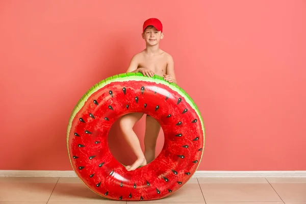 Ragazzo carino con anello gonfiabile vicino alla parete di colore — Foto Stock