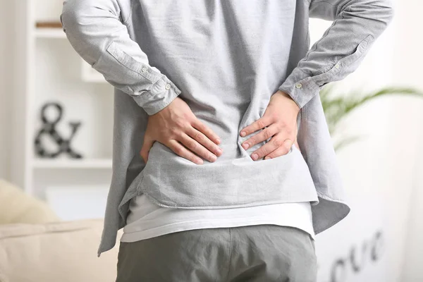 Young man suffering from back pain at home — Stock Photo, Image