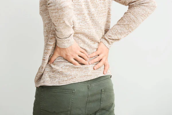 Young man suffering from back pain on white background — Stock Photo, Image