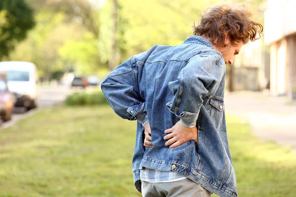 Jonge man die lijdt aan rugpijn buitenshuis — Stockfoto