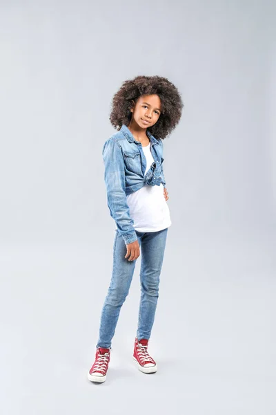 Stilvolles afrikanisch-amerikanisches Mädchen in Jeans-Kleidung auf grauem Hintergrund — Stockfoto