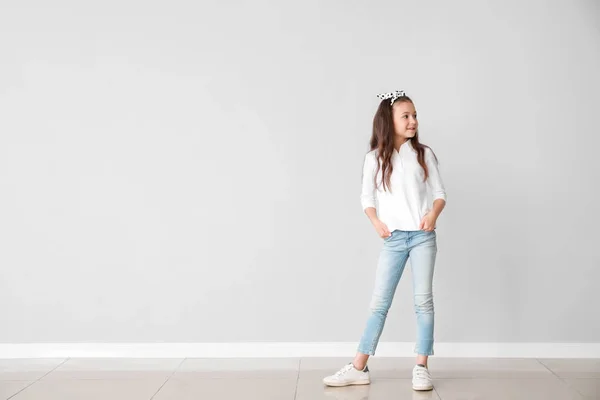 Stylová dívka v džínách u světlé zdi — Stock fotografie