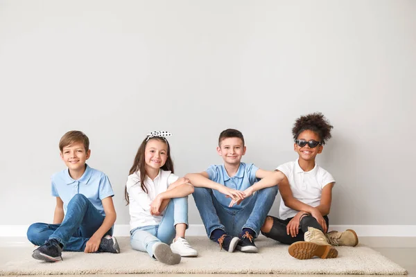 Stylish children in jeans sitting near light wall — Stock Photo, Image