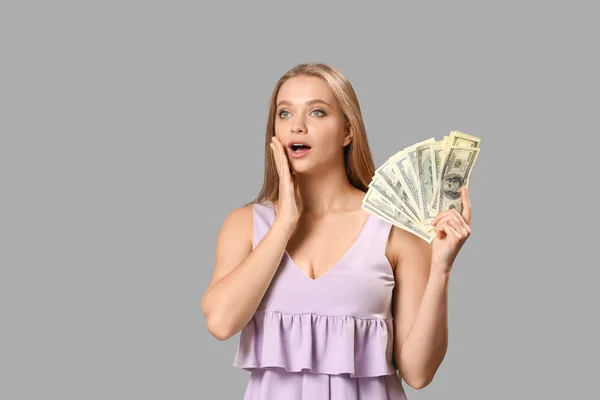 Troubled woman with money on grey background — Stock Photo, Image