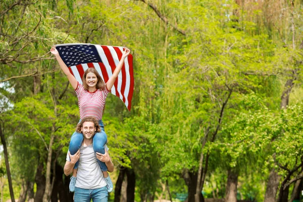 Jovem casal feliz com bandeira dos EUA ao ar livre. Celebração do dia da independência — Fotografia de Stock