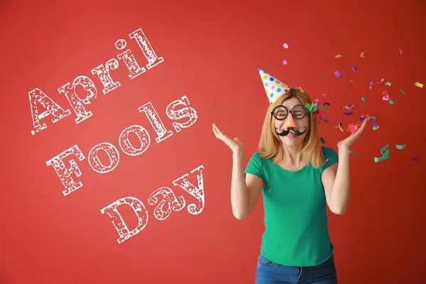 Funny woman with party decor and confetti on color background. April Fools' Day celebration — Stock Photo, Image