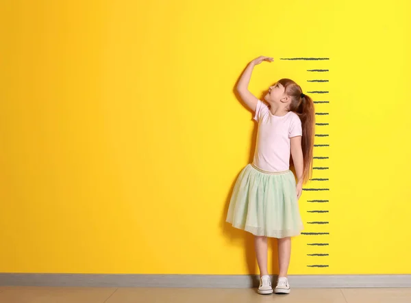 Ładna dziewczynka pomiaru wysokości blisko kolor ściany — Zdjęcie stockowe