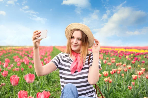 Schöne junge Frau macht Selfie im Tulpenfeld an einem Frühlingstag — Stockfoto
