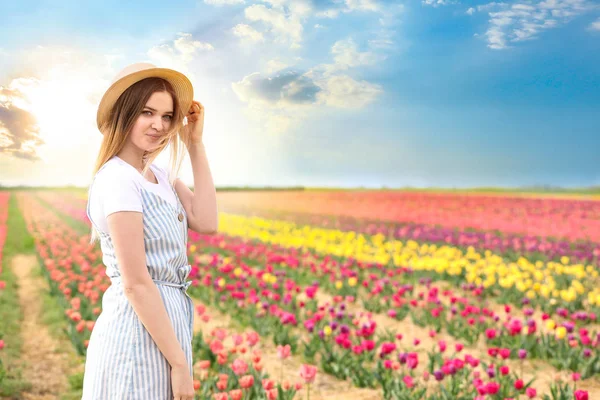 Beautiful young woman in tulip field on spring day — Stock Photo, Image