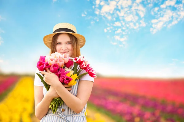 Beautiful young woman in tulip field on spring day — Stock Photo, Image