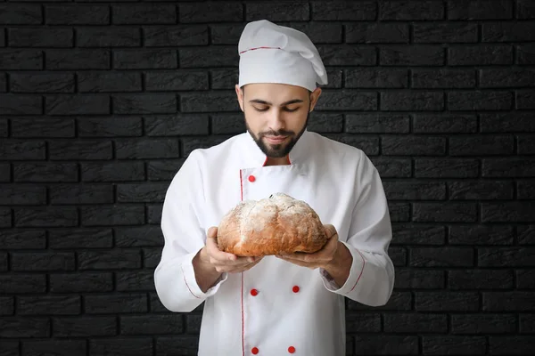 Kuchař s čerstvým chlebem na tmavém pozadí — Stock fotografie