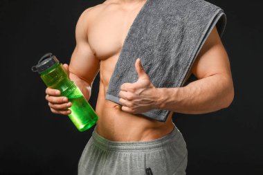 Karanlık arka planda su şişesi ile sportif adam