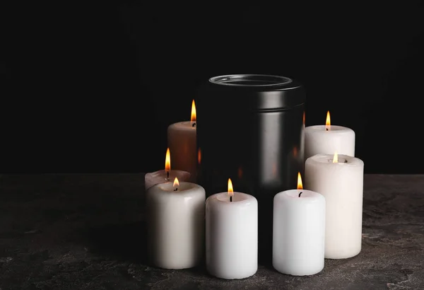 Urna funeraria con velas encendidas sobre la mesa sobre fondo oscuro — Foto de Stock