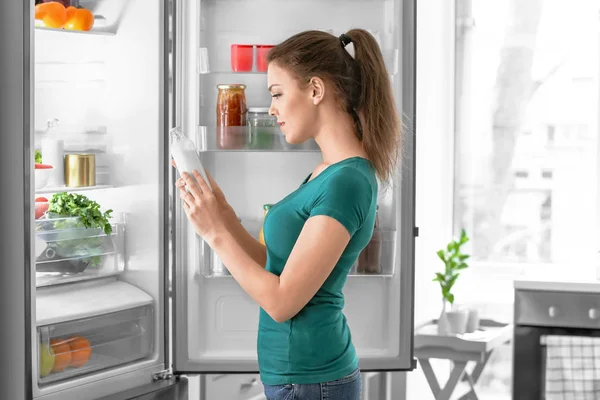 Mujer sacando comida de la nevera en casa — Foto de Stock