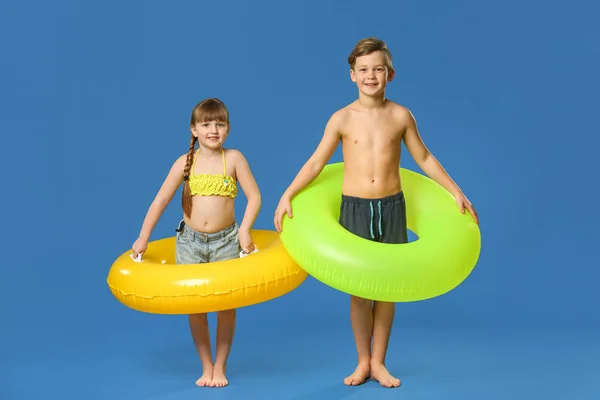 Милі маленькі діти з надувними кільцями на кольоровому фоні — стокове фото