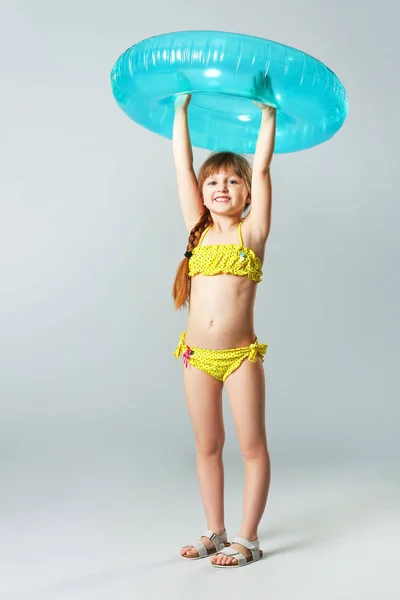 Cute Little Girl z nadmuchiwanym pierścieniem na szarym tle — Zdjęcie stockowe