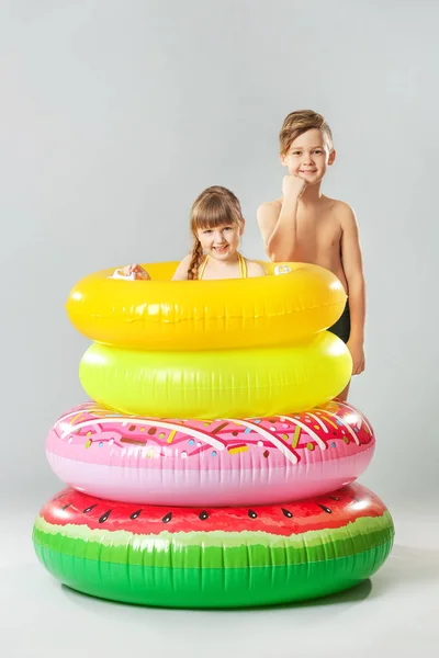 Lindos niños pequeños con anillos inflables en el fondo de color —  Fotos de Stock