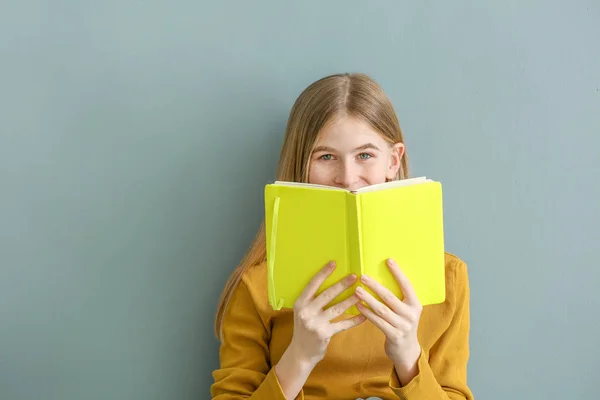 Retrato de linda adolescente con libro sobre fondo de color — Foto de Stock