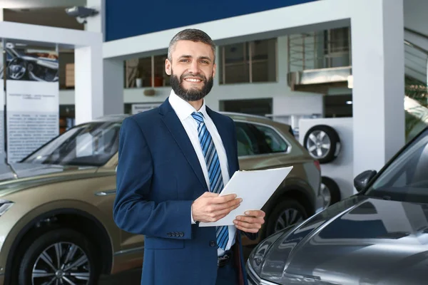 Salesman in modern car showroom — Stock Photo, Image