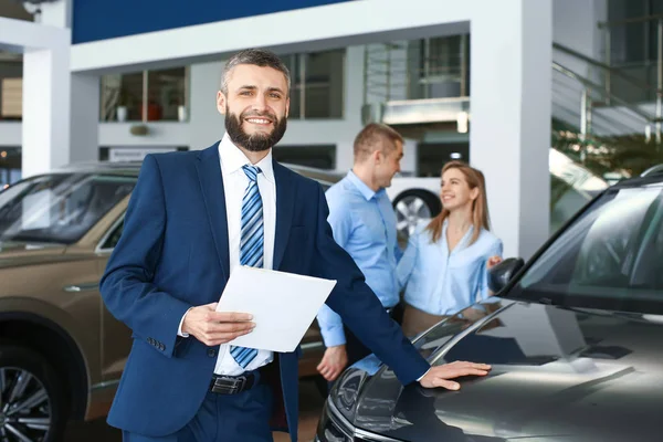 Salesman in modern car showroom — Stock Photo, Image