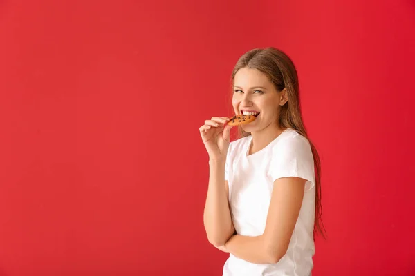 Piękna młoda kobieta z smacznym ciasteczko na kolorowym tle — Zdjęcie stockowe