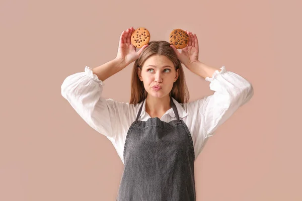 Emotional female baker with tasty cookies on color background — Stock Photo, Image