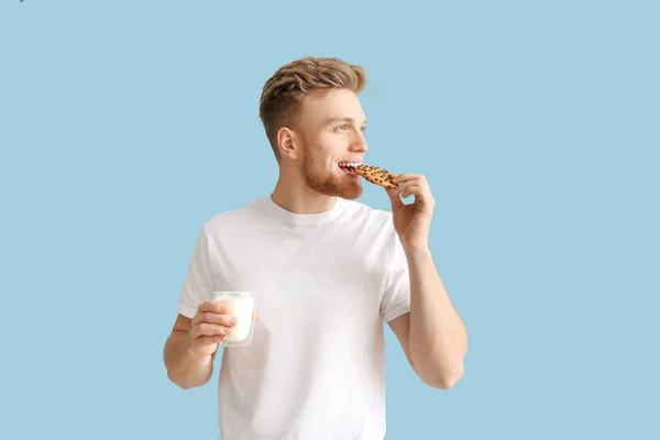 잘 생긴 젊은 남자 와 맛있는 쿠키 와 유리 의 우유 에 색상 배경 — 스톡 사진