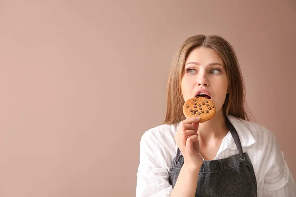 색상 배경에 맛있는 쿠키와 아름다운 여성 베이커 — 스톡 사진