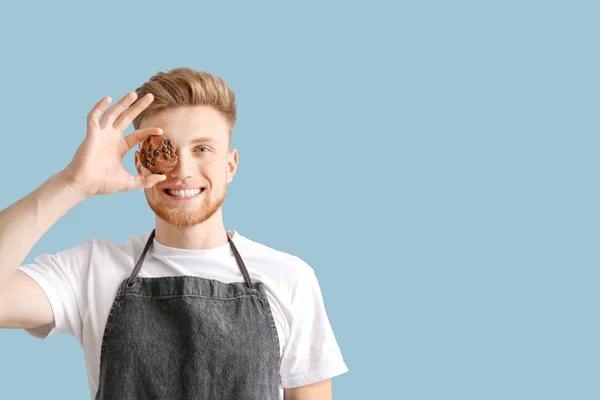Happy male baker with tasty cookies on color background — Stock Photo, Image
