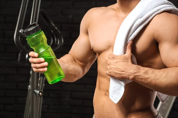 Sporty man with bottle of water on dark background — Stock Photo, Image