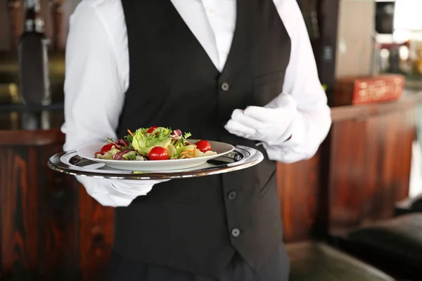 Young male waiter with salad in restaurant, closeup — Stock Photo, Image