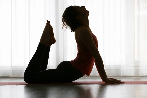 Silueta de joven deportista practicando yoga en interiores — Foto de Stock