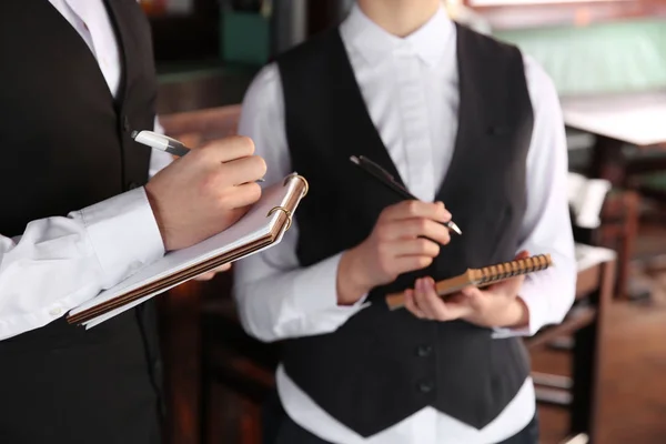 Jóvenes camareros con cuadernos en el restaurante — Foto de Stock