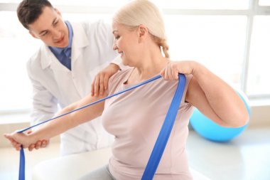 Rehabilitasyon merkezinde olgun hasta ile çalışan fizyoterapist