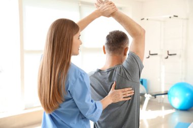 Rehabilitasyon merkezinde olgun hasta ile çalışan fizyoterapist