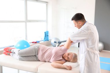 Rehabilitasyon merkezinde olgun hasta ile çalışan fizyoterapist