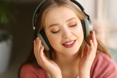 Evde müzik dinleyen güzel genç bir kadın.