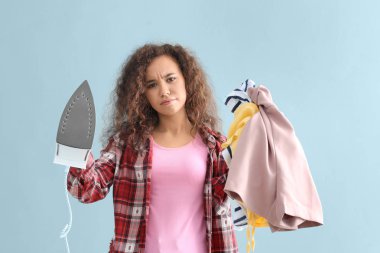 Gri arka planda demir ve giysi ile stresli kadın