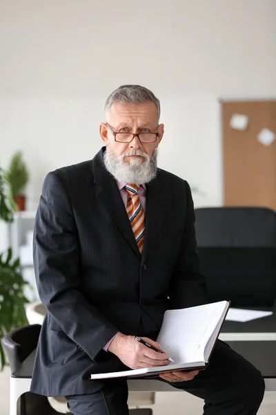 Handsome mature businessman with notebook in office — Stock Photo, Image