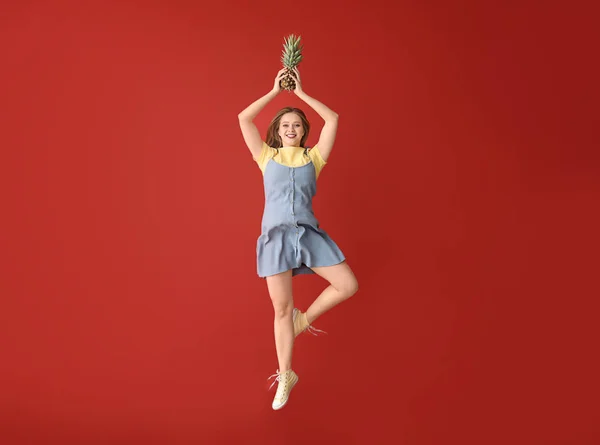 Jumping woman with pineapple on color background — Stock Photo, Image