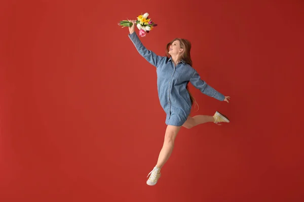 Springende vrouw met boeket van bloemen op kleur achtergrond — Stockfoto