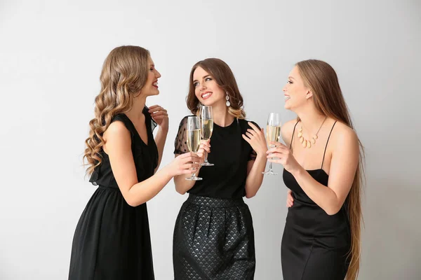 Lindas mulheres jovens com copos de champanhe no fundo claro — Fotografia de Stock
