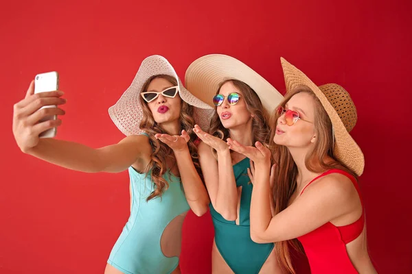 Schöne junge Frauen in Badeanzügen machen Selfie auf farbigem Hintergrund — Stockfoto