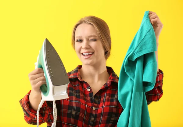 Jonge vrouw met ijzer en kleren op kleur achtergrond — Stockfoto