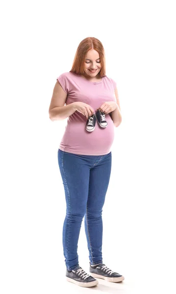 Bella donna incinta con stivaletti bambino su sfondo bianco — Foto Stock