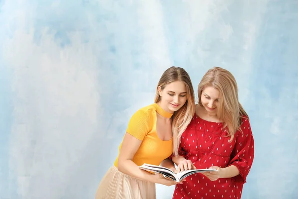 Retrato de madre e hija leyendo revista sobre fondo de color — Foto de Stock