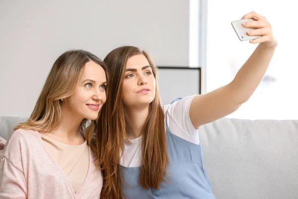Portrait of happy mother and daughter taking selfie at home — Stock Photo, Image